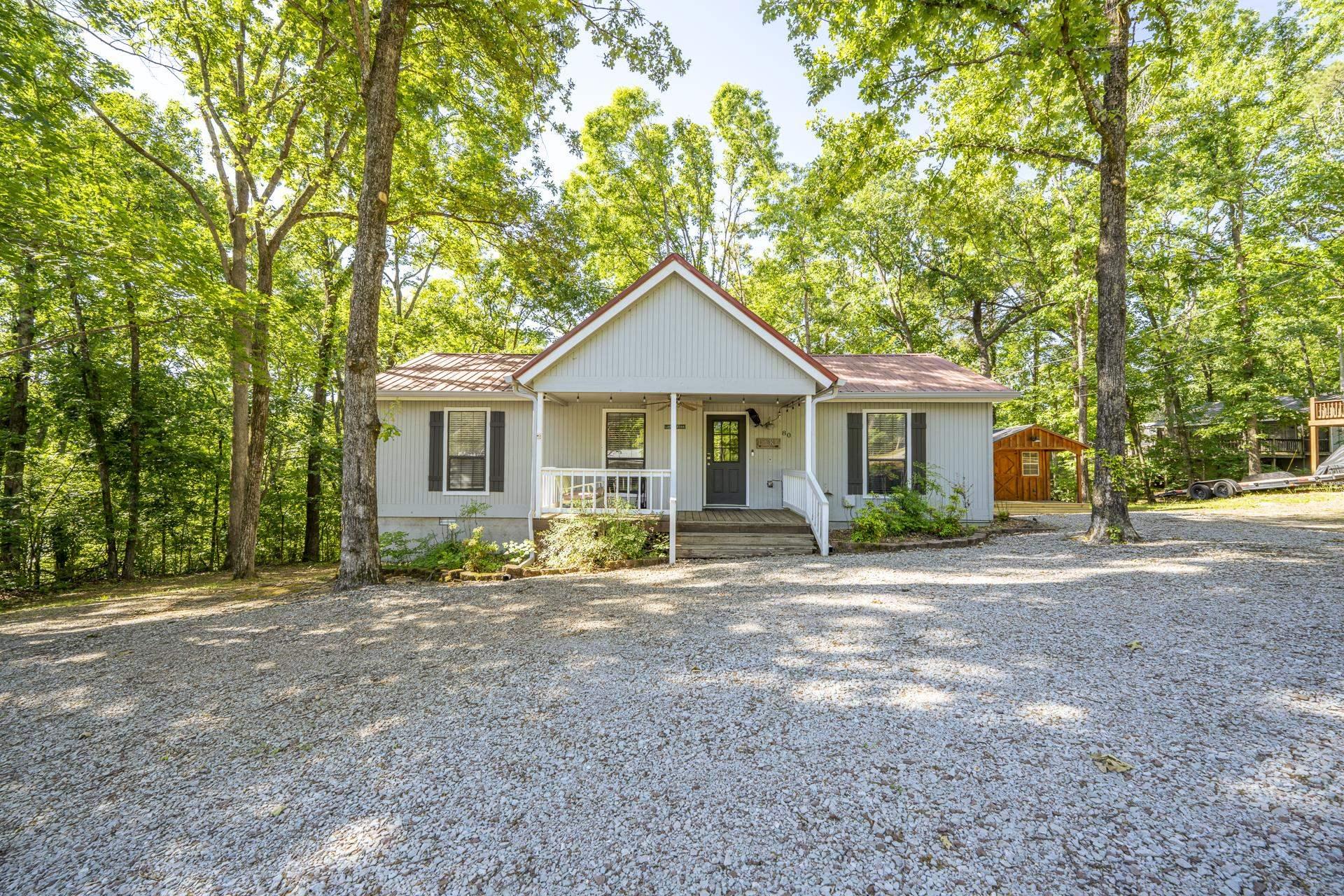 Image 2: Light gray siding exterior with a red roof, a covered front porch, and white railing