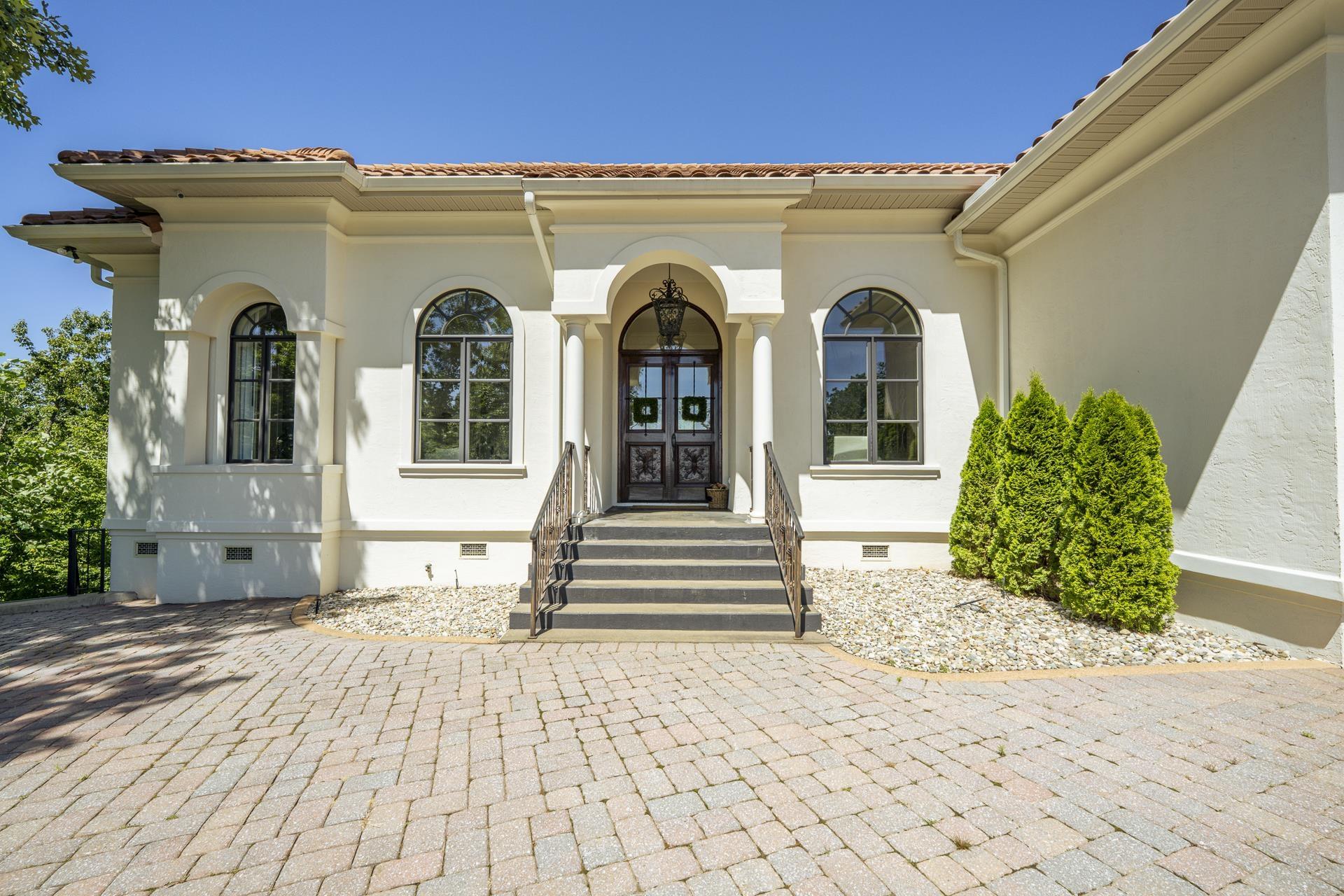 Image 2: Stucco exterior featuring a tile roof and arched windows