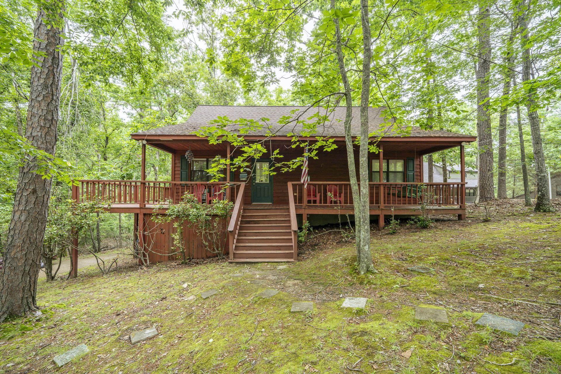 Image 1: Wood-sided cabin featuring a covered front porch with railings and steps