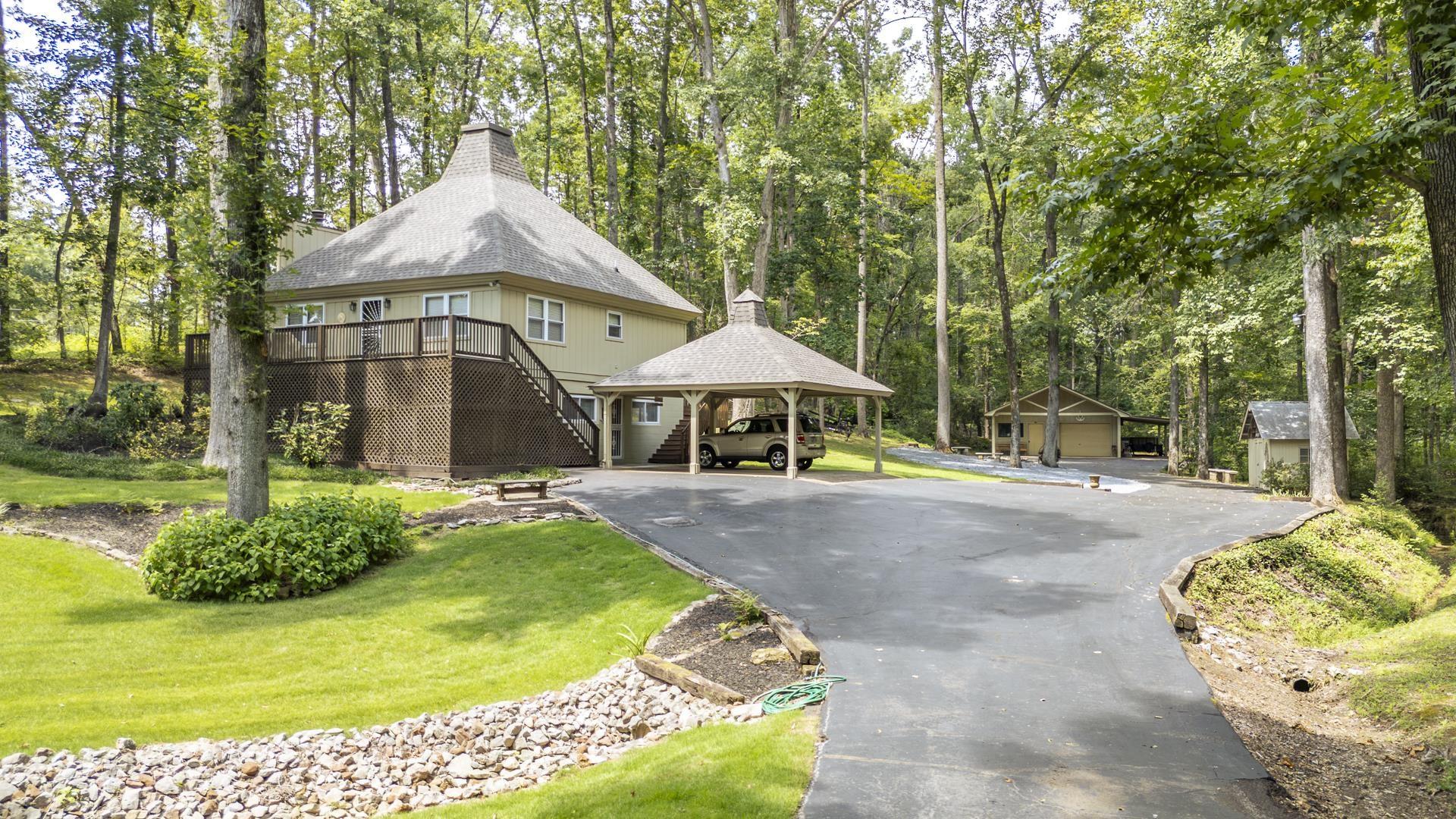 Image 2: Distinctive architectural residence nestled on a wooded lot, featuring a striking conical roof design with multiple peaked elements
