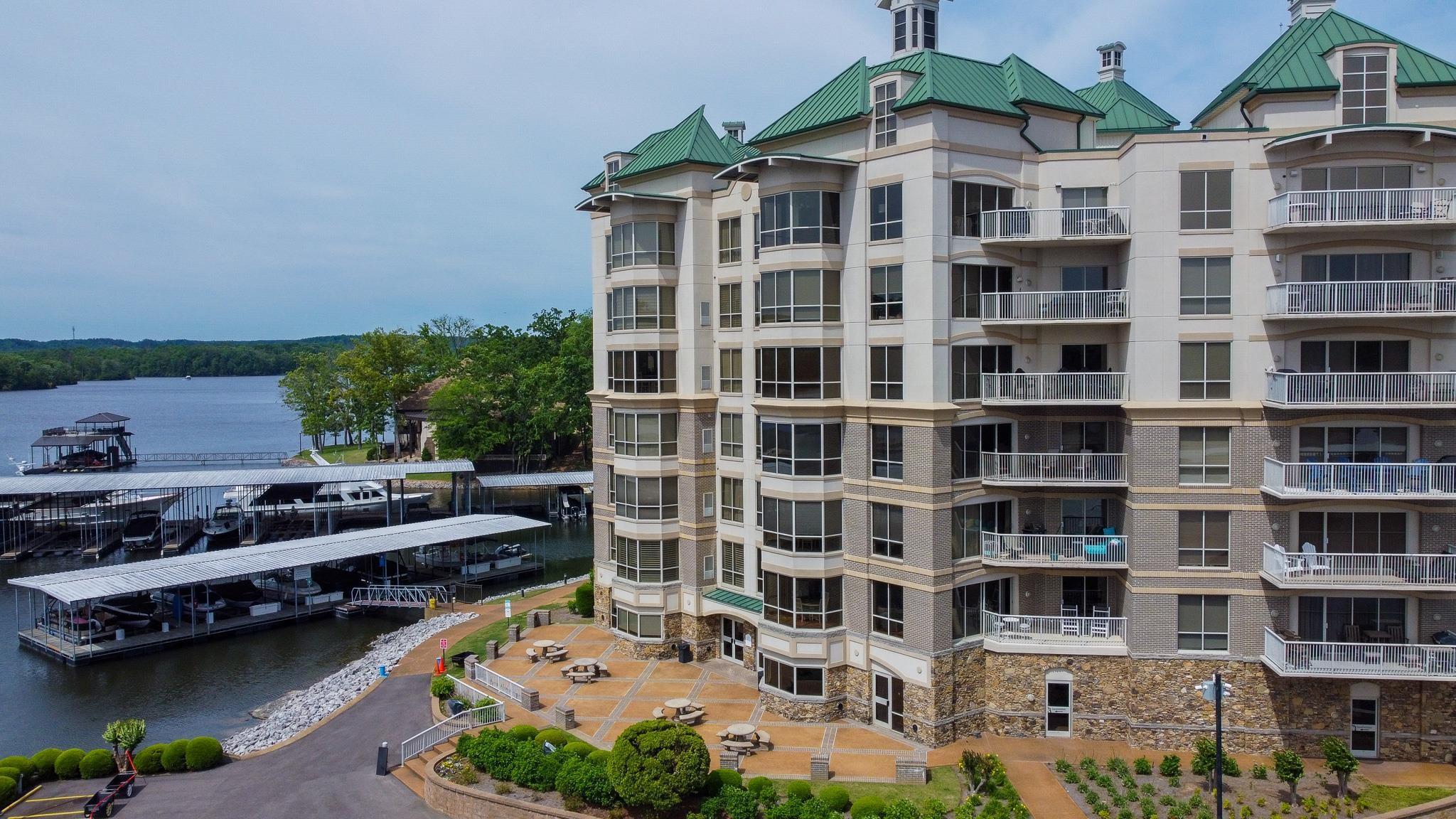 Image 2: Waterfront condominium building featuring multiple private balconies, a stone and stucco facade, and green hip roofs