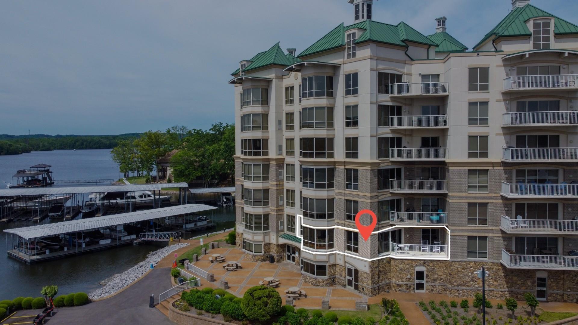 Image 3: Waterfront condominium building with covered boat slips, multiple balconies, and stone facade accents