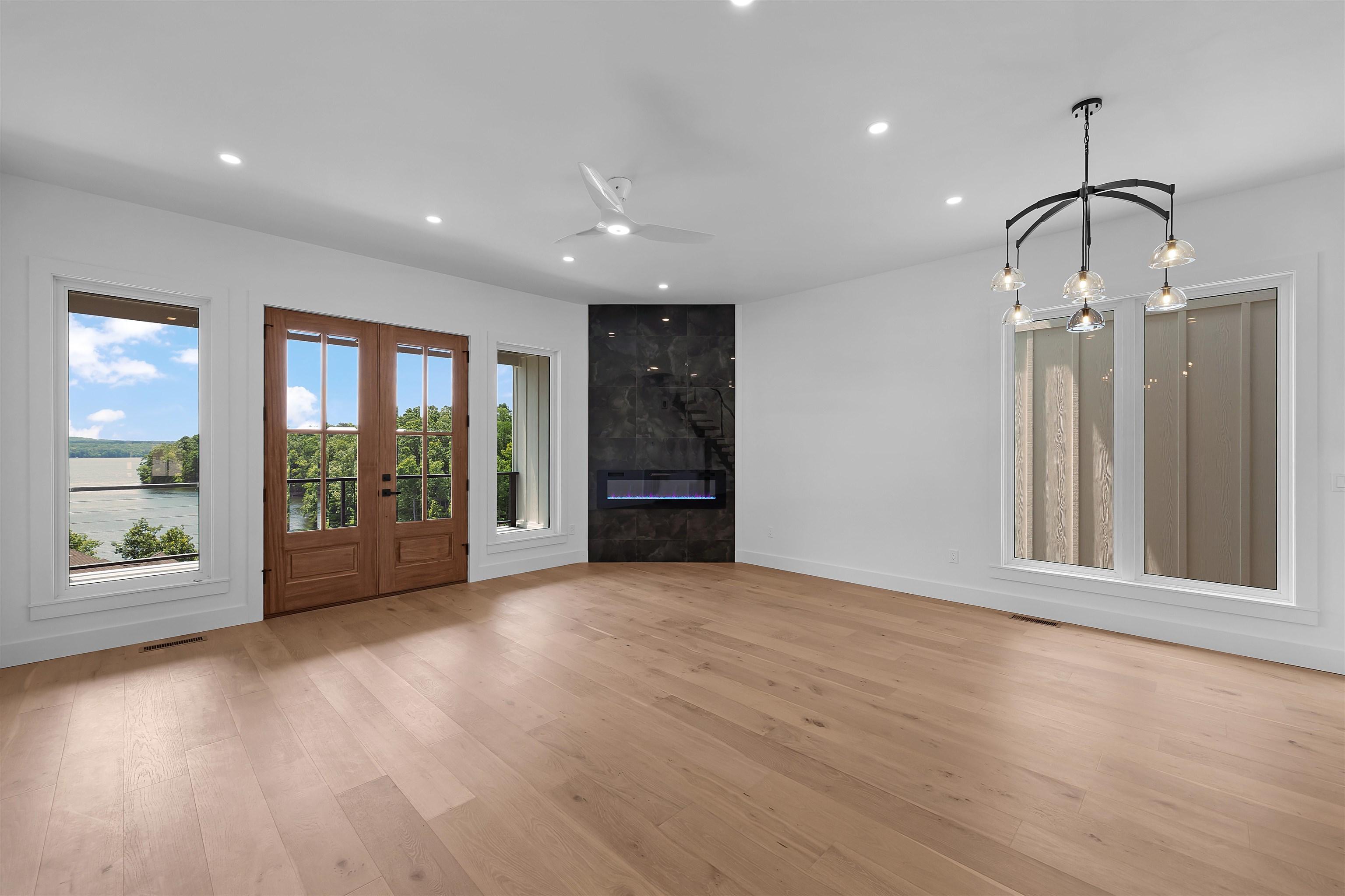 Image 4: Spacious room featuring light wood-finish flooring, a contemporary fireplace with a dark stone-look surround, and recessed lighting