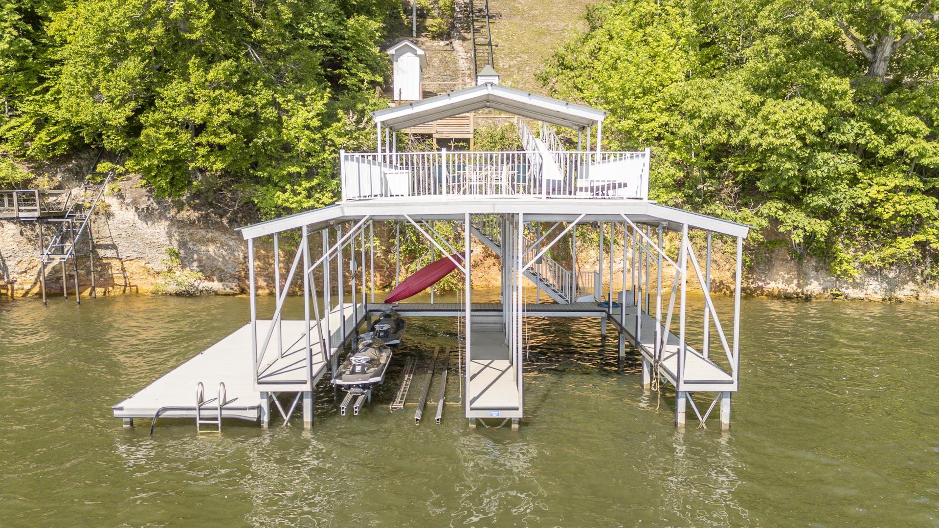 Image 2: Two-story boat dock featuring a covered upper deck, dual boat slips with lifts, an extended floating dock, and dual swim ladders