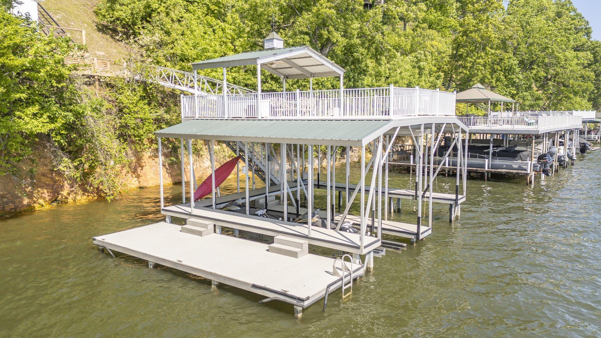 Image 4: Two-story dock structure featuring a covered boat slip, open-air upper deck with white railings, and a lower platform with a boarding ladder