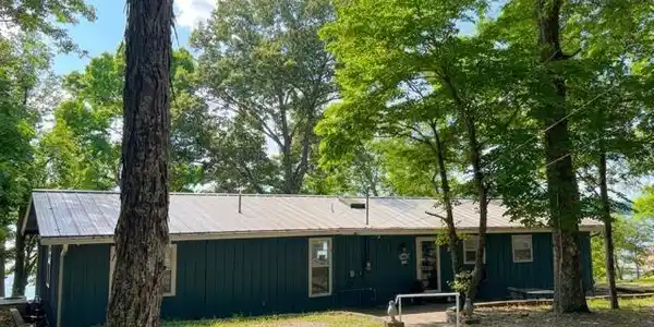 Image 4: Single-story structure with teal siding and a metal roof