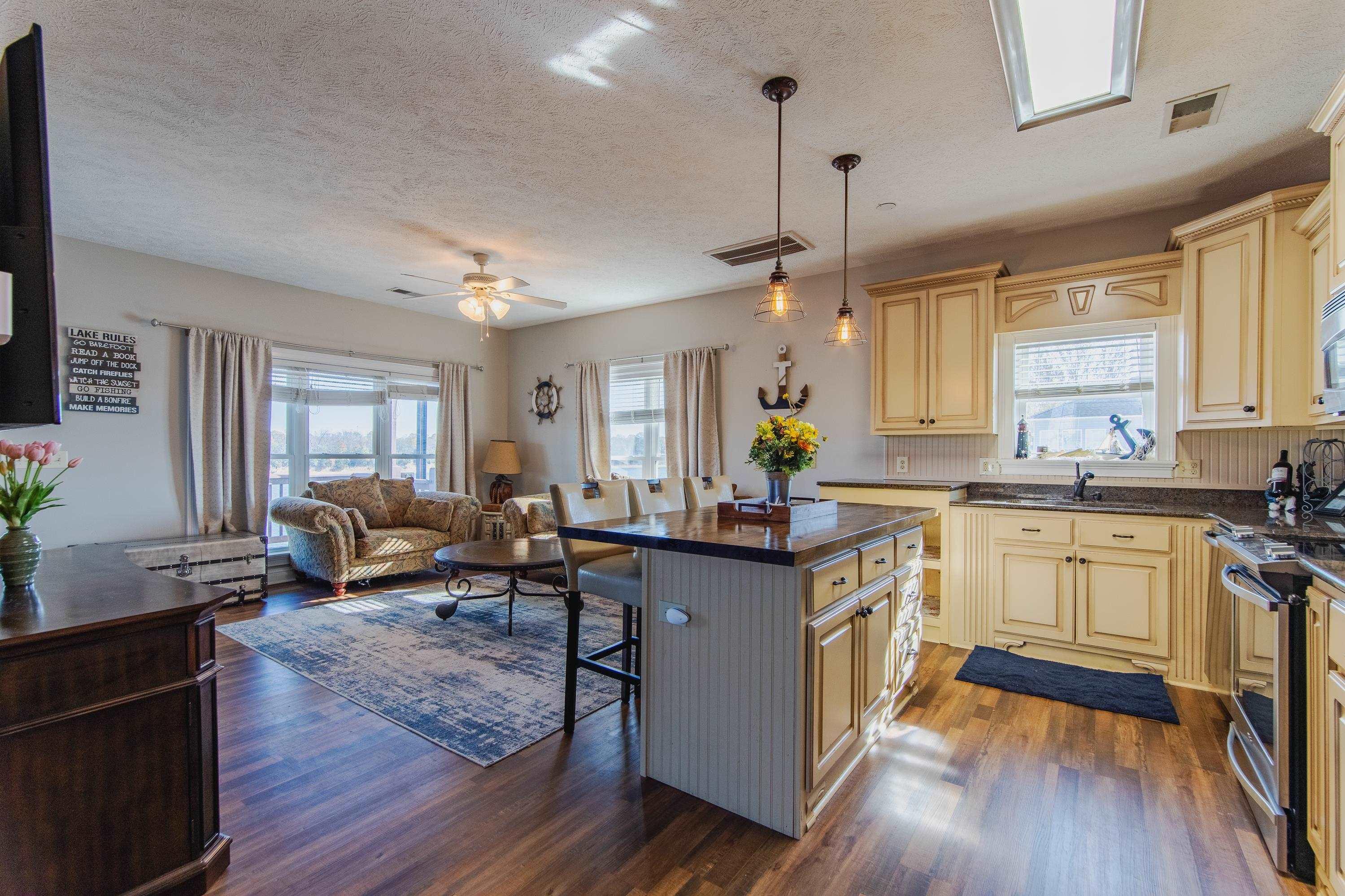 Image 3: Kitchen featuring a center island, dark wood-type flooring, a kitchen breakfast bar, hanging light fixtures, and stainless steel stove