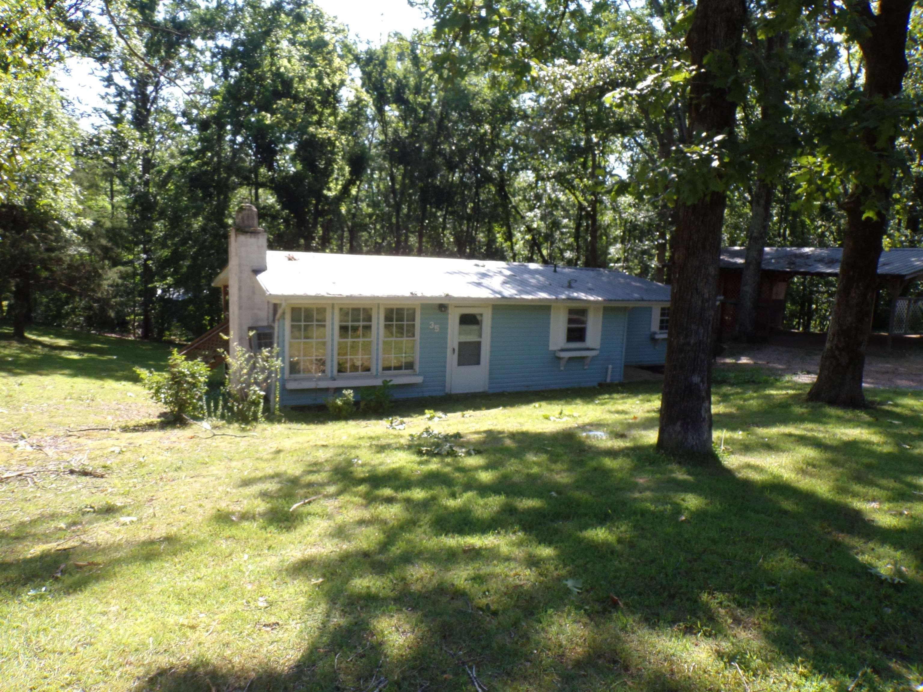 Image 2: Light blue exterior featuring a prominent chimney, a white front door, and a row of large windows