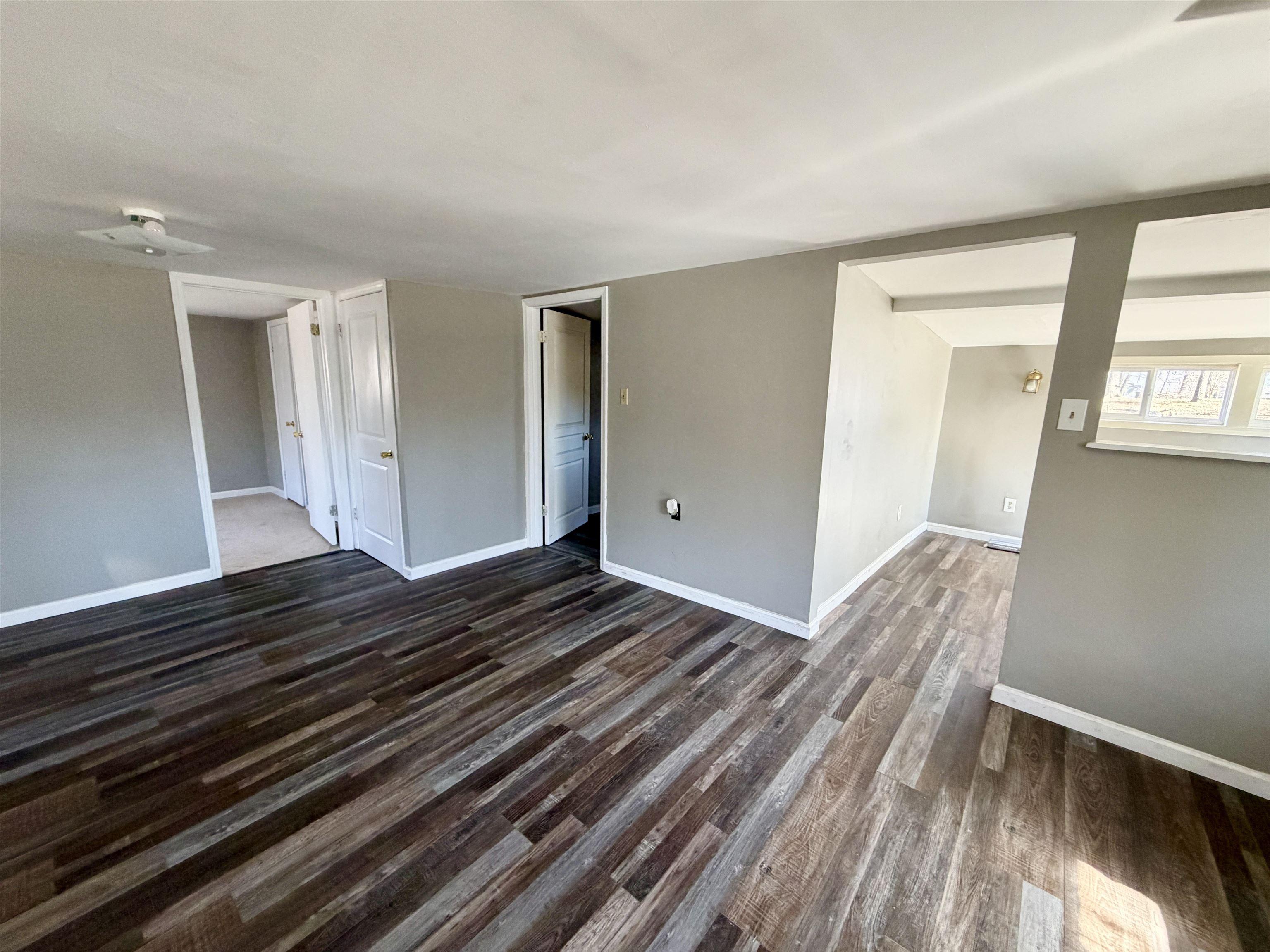 Image 4: Unfurnished living room with dark wood-type flooring and baseboards