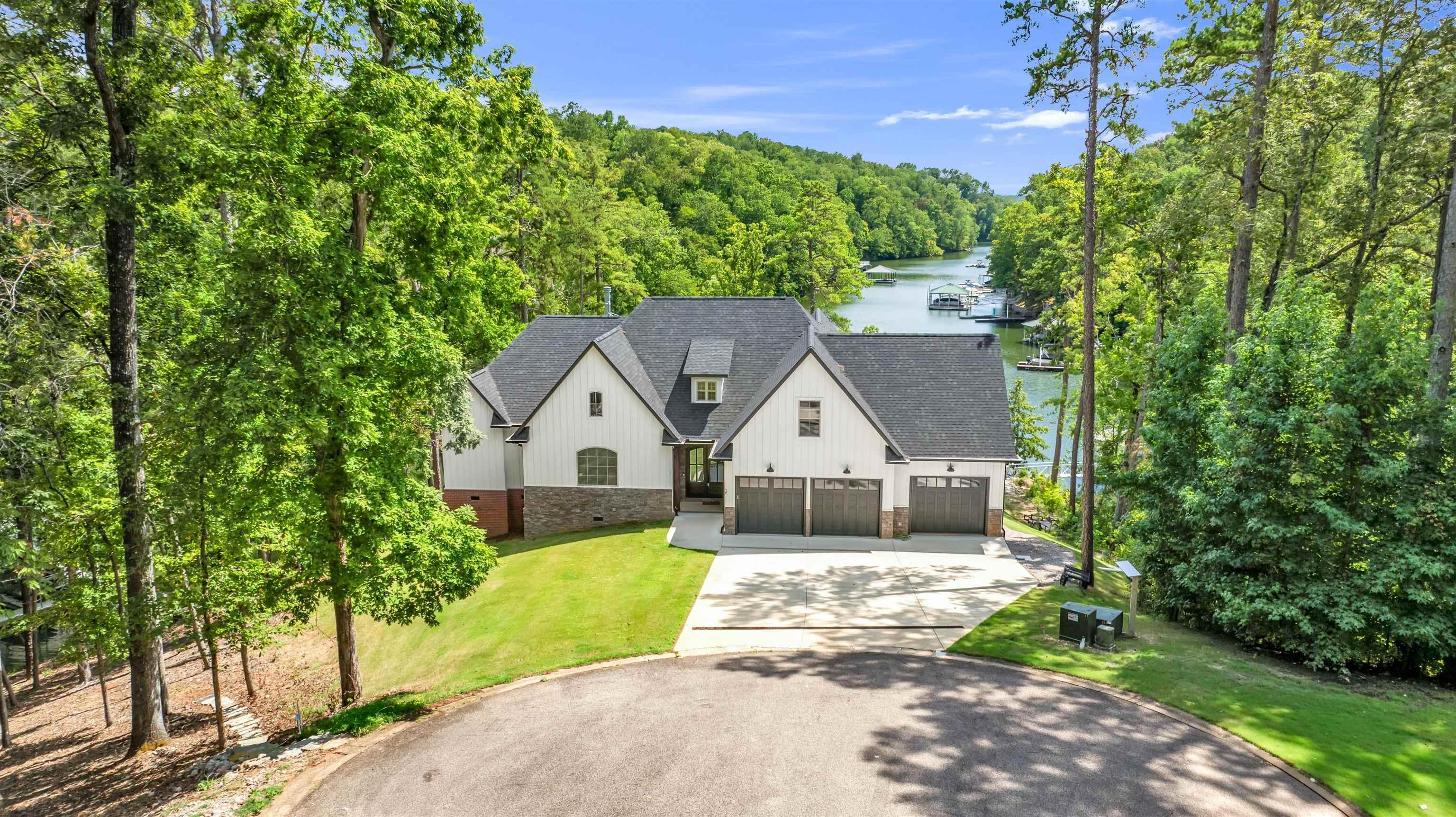 Image 2: Modern farmhouse style home featuring driveway, roof with shingles, a water view, a front lawn, and brick siding