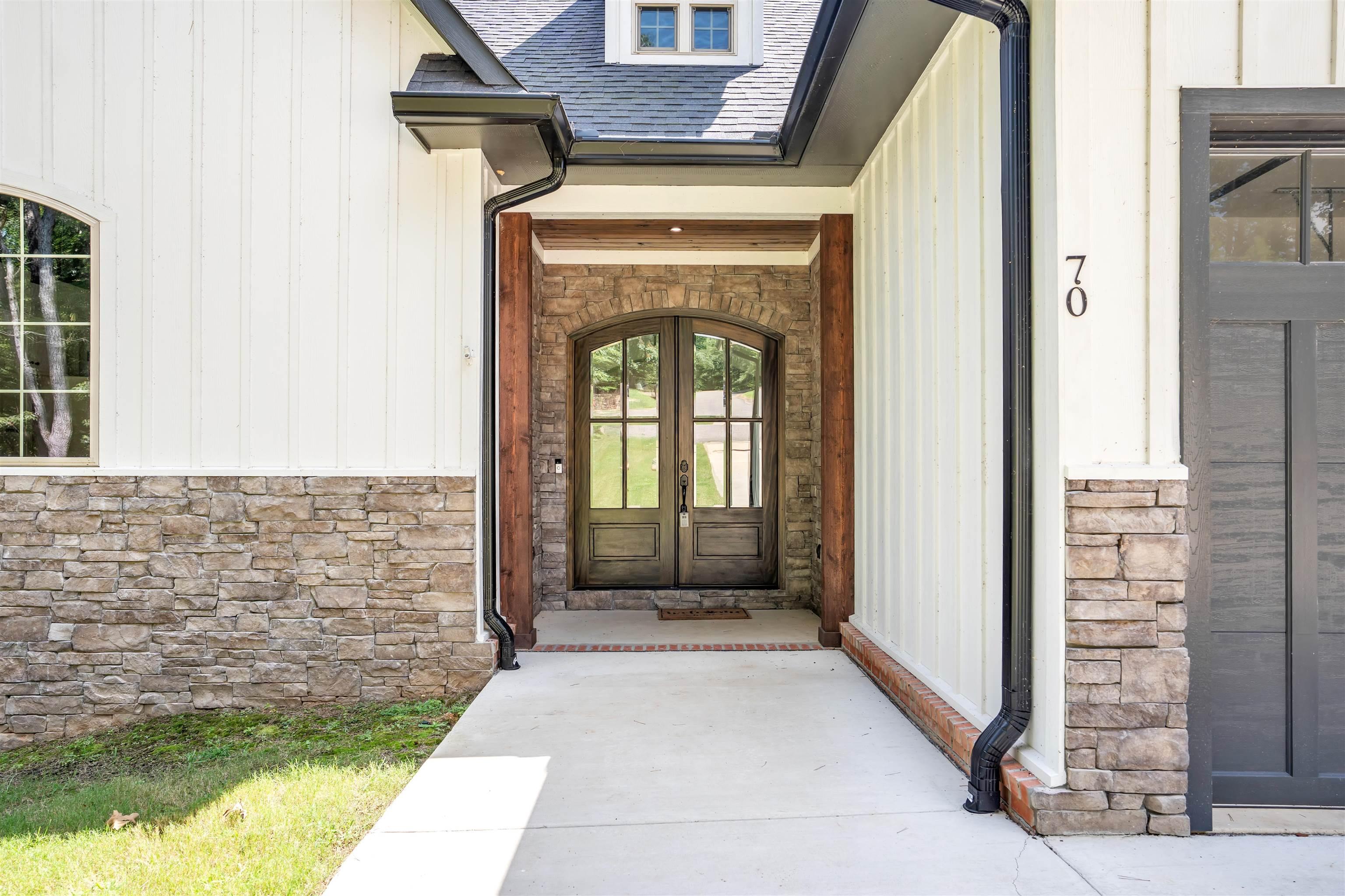 Image 3: Entrance to property featuring stone siding, a shingled roof, and french doors