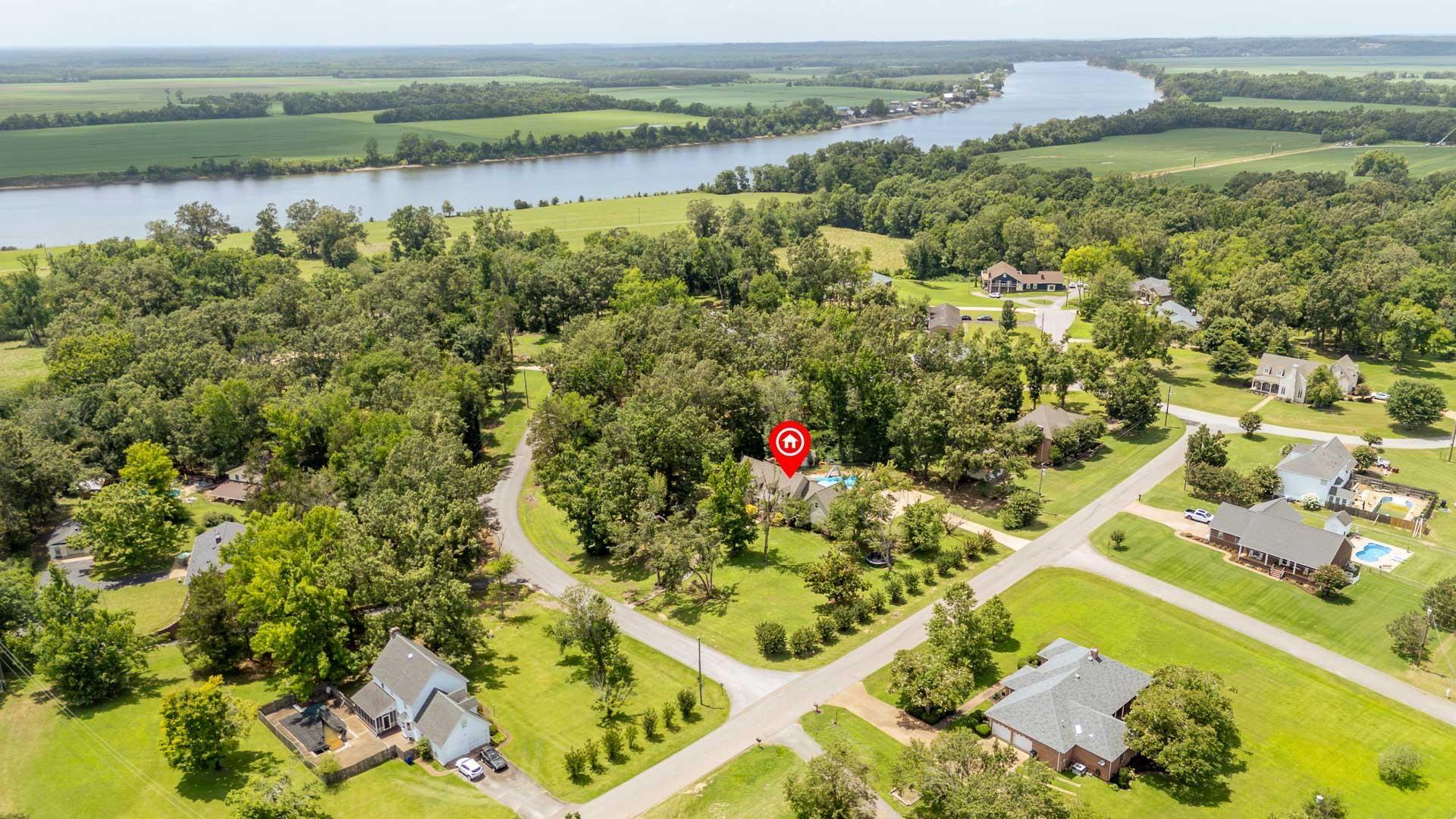Image 2: Expansive rural property featuring a large body of water, mature trees, and a residential community