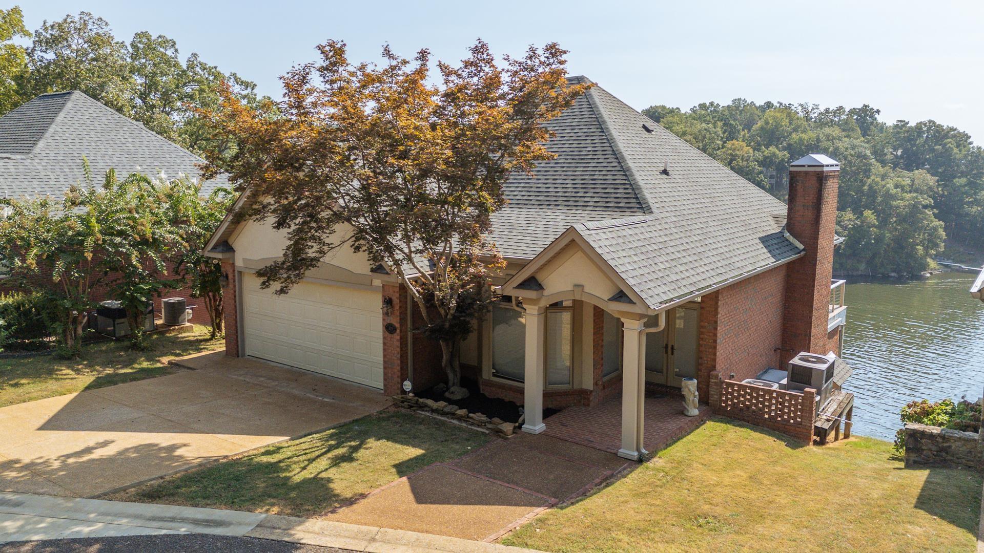 Image 3: View of front of property with roof with shingles, brick siding, driveway, a chimney, and a garage