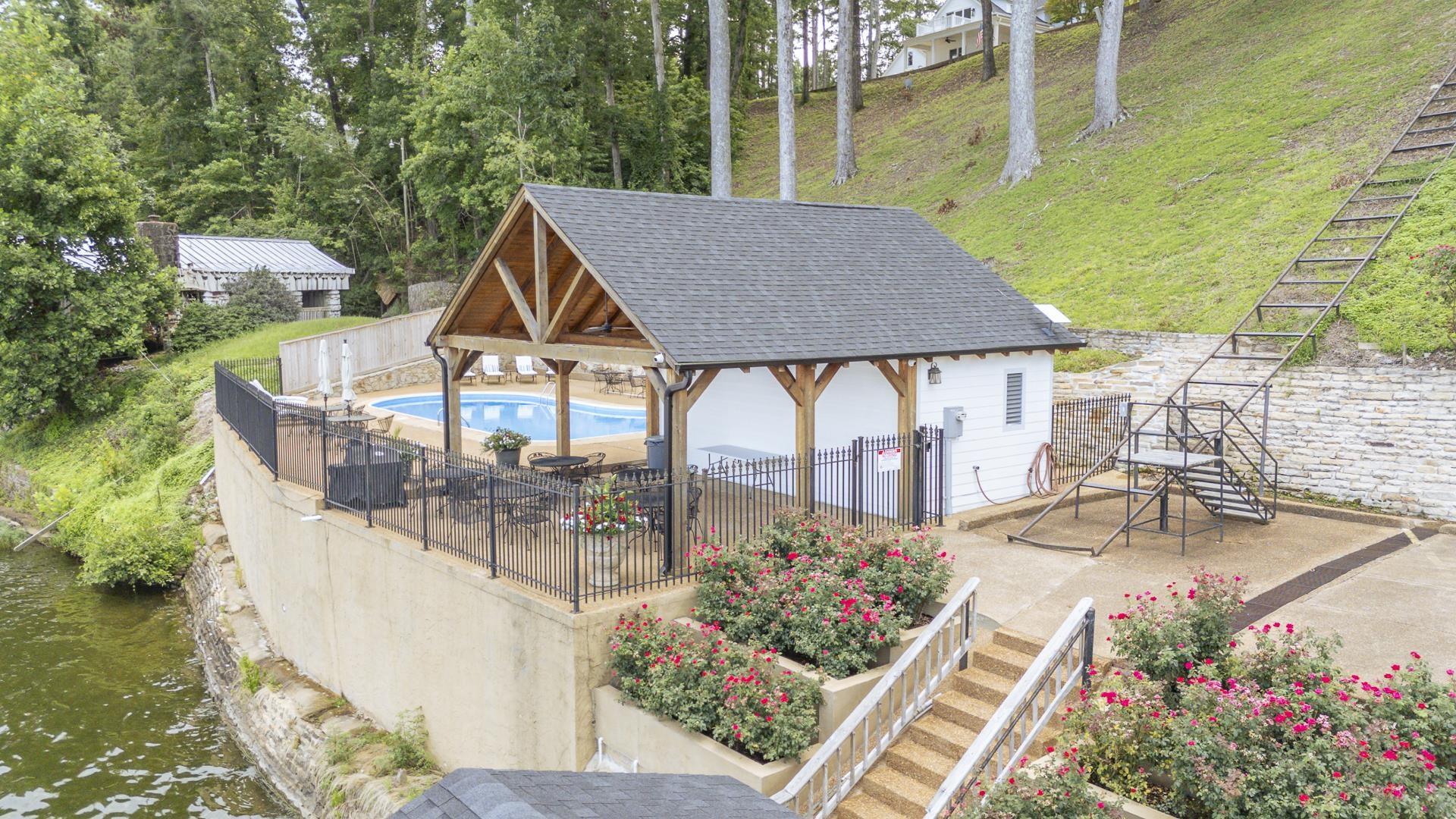 Image 3: Outdoor leisure area featuring a covered pool structure, an in-ground swimming pool, a patio area with outdoor seating, and a hillside tram system