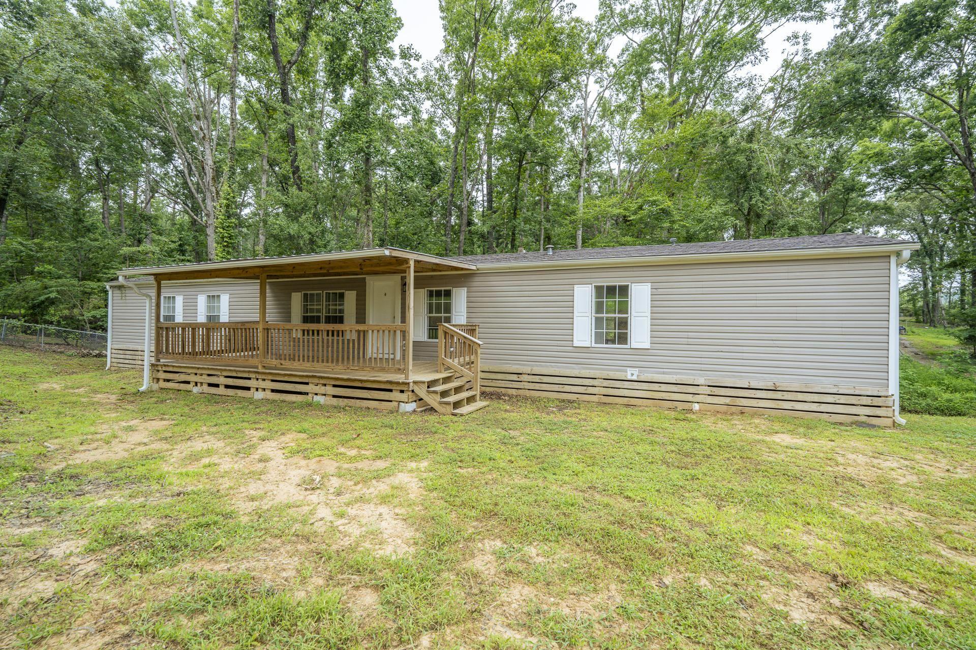 Image 4: Exterior featuring light gray siding, white window shutters, and a covered wood deck