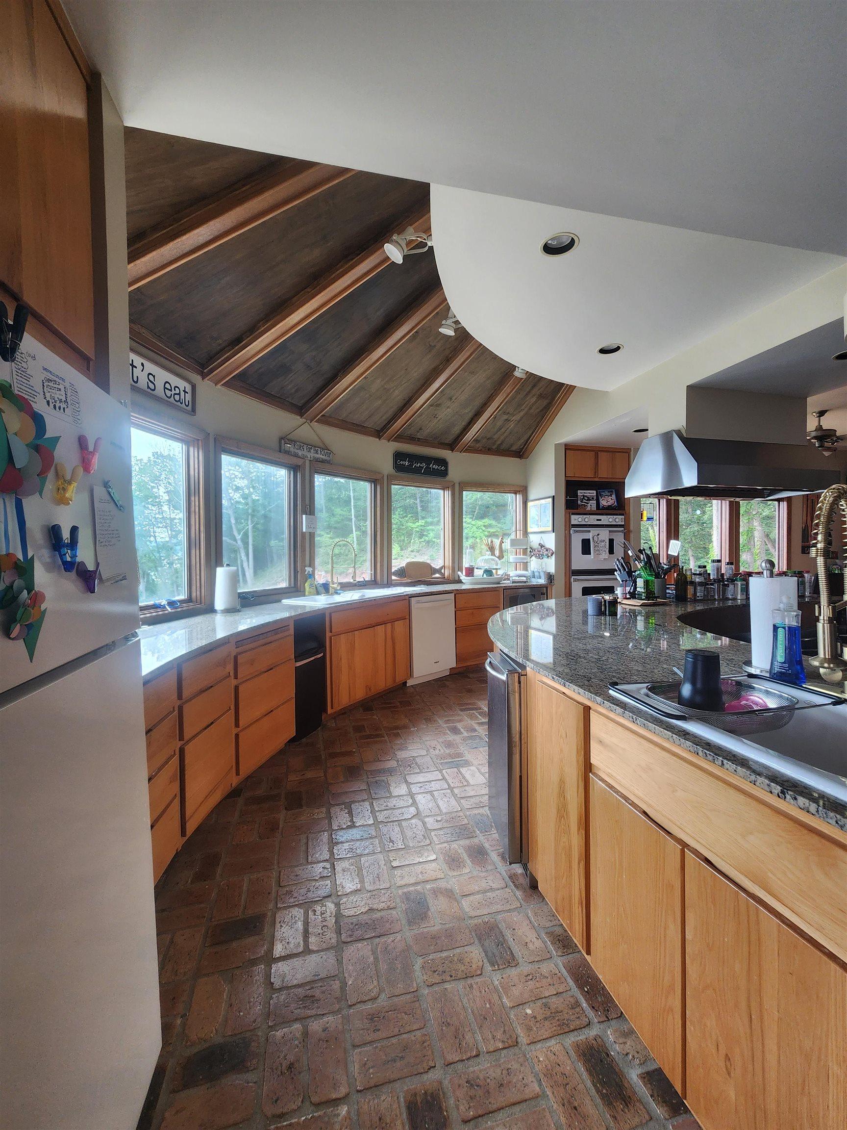 Image 3: Kitchen with white appliances, brick flooring, vaulted ceiling, recessed lighting, and plenty of natural light