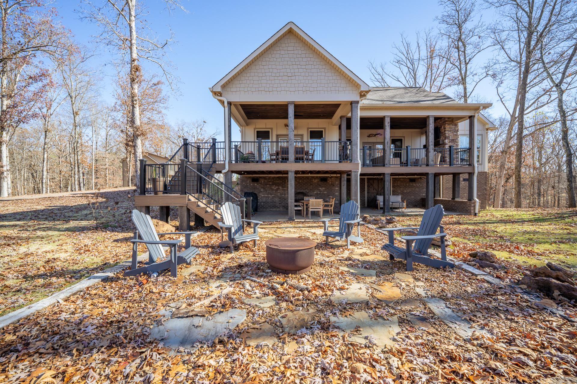 Image 3: Rear view of house featuring board and batten siding, a wooden deck, a patio area, and an outdoor fire pit