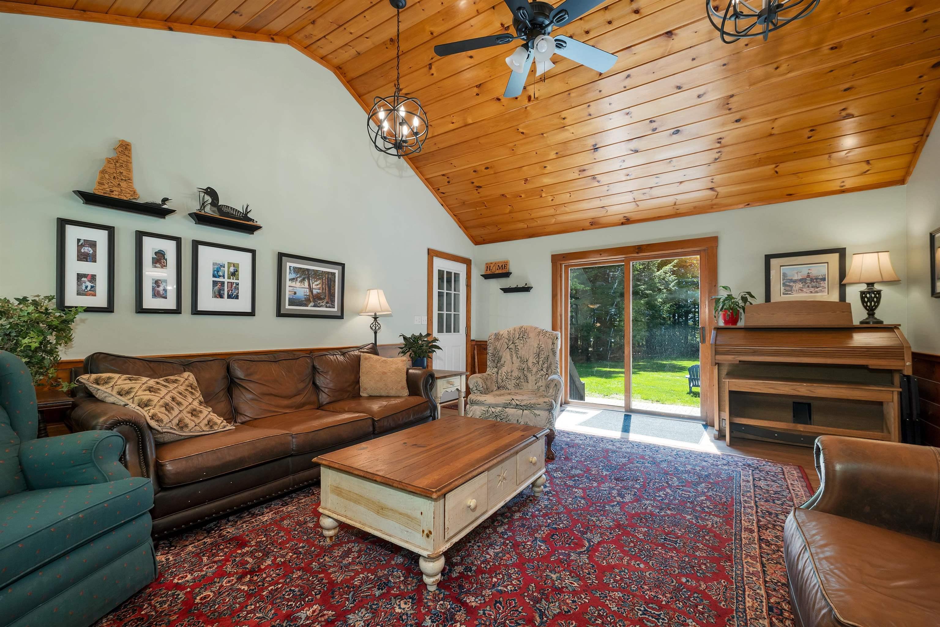 Image 3: A bright living room with vaulted wood ceilings and backyard