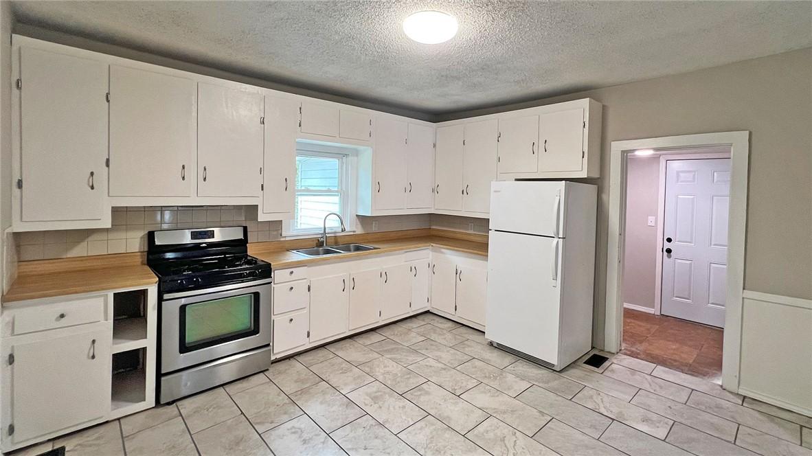 Image 3: Kitchen featuring white cabinetry, wood-finish cou