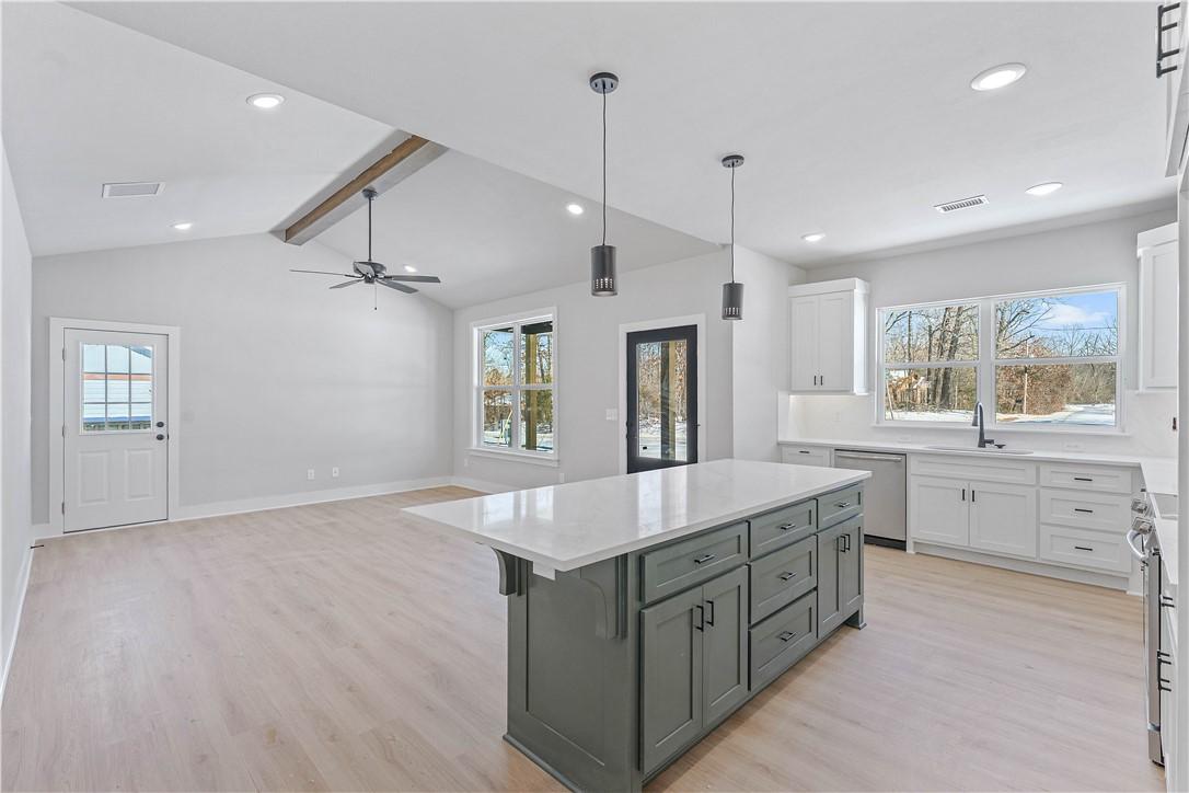 Image 2: Kitchen featuring white cabinetry, hanging light f