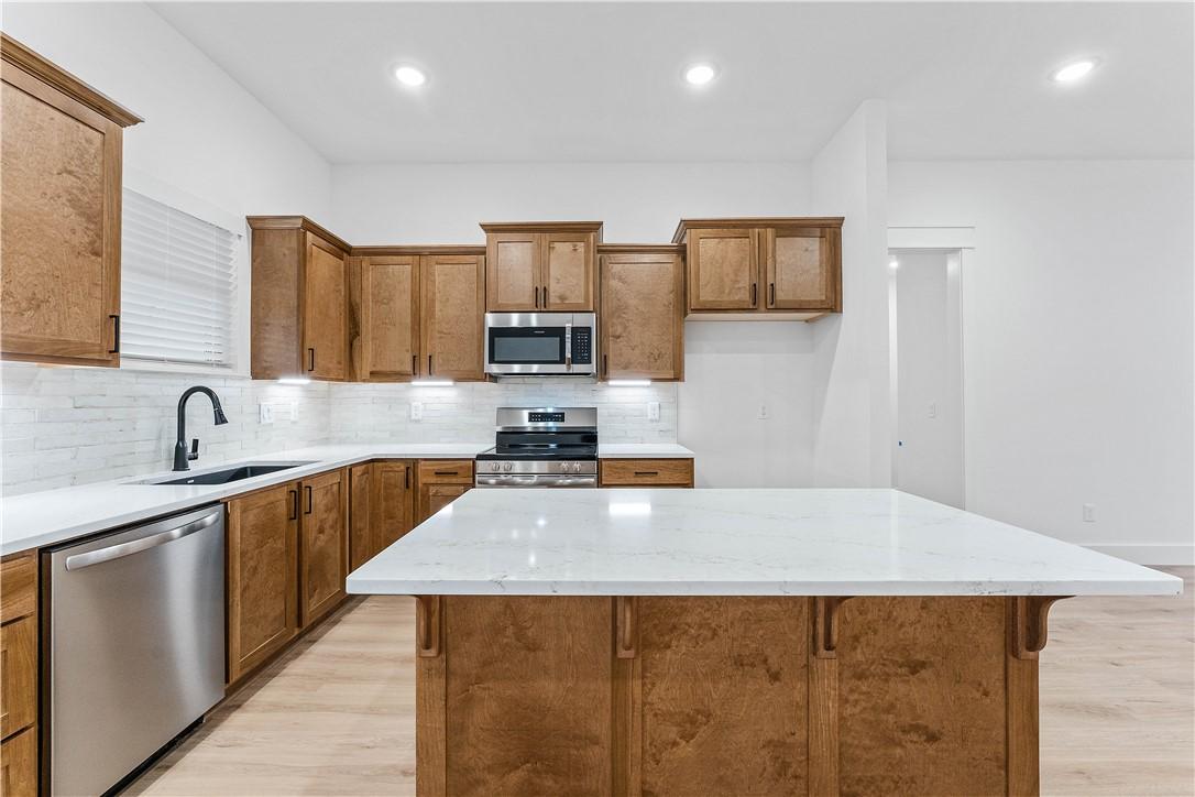 Image 2: Kitchen with brown cabinets, appliances with stain
