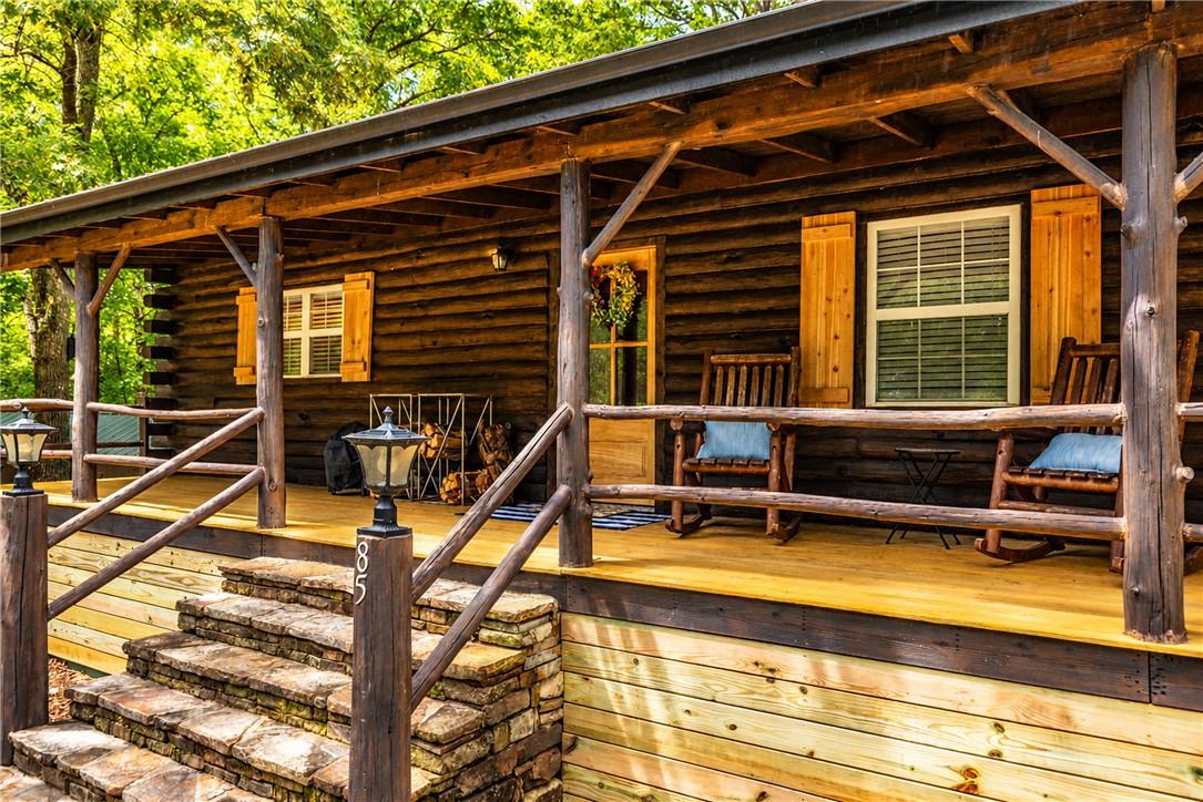 Image 3: Rustic log cabin exterior featuring a covered wood