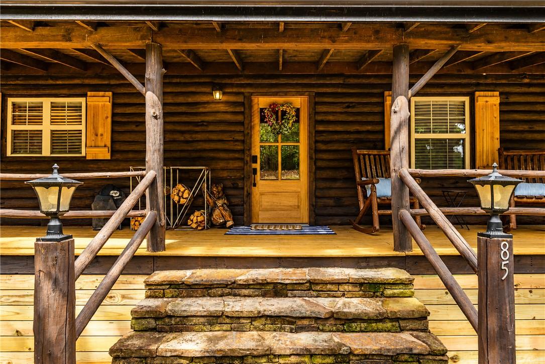 Image 4: Rustic log cabin exterior featuring a covered porc