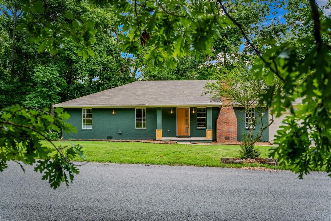 Image 1: Ranch-style exterior with a dark green facade and