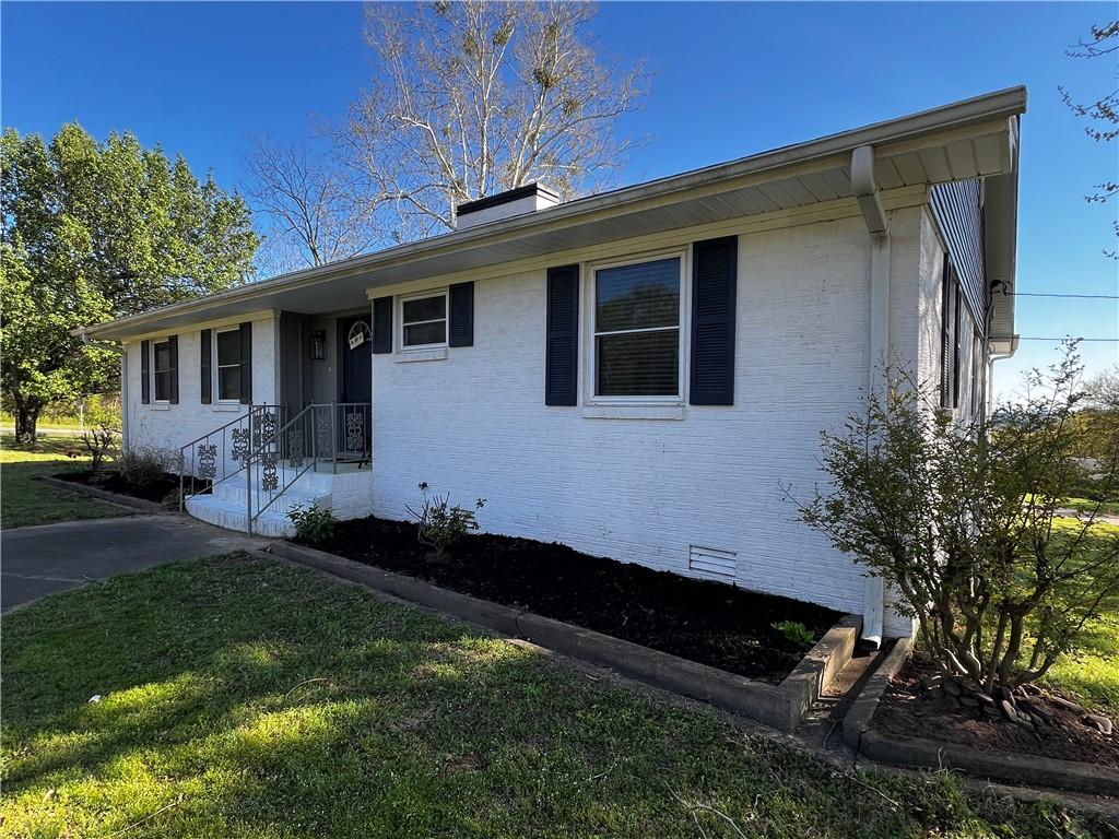 Image 2: White brick exterior with dark shutters, featuring