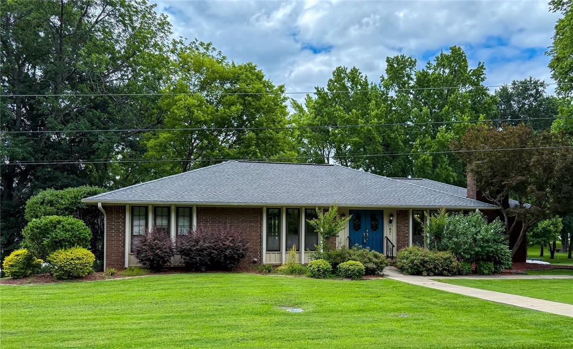 Image 1: Brick ranch-style residence featuring a dark shing