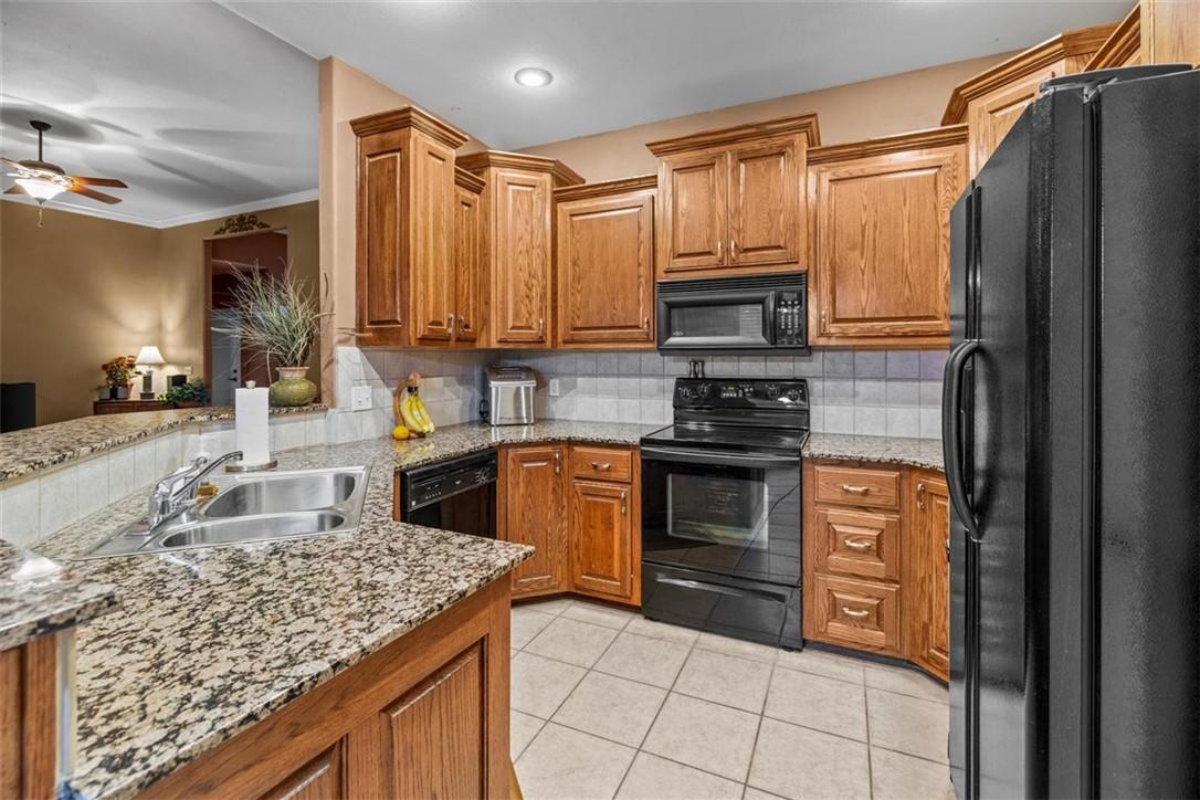 Image 3: Kitchen featuring wood cabinetry, granite-finish c