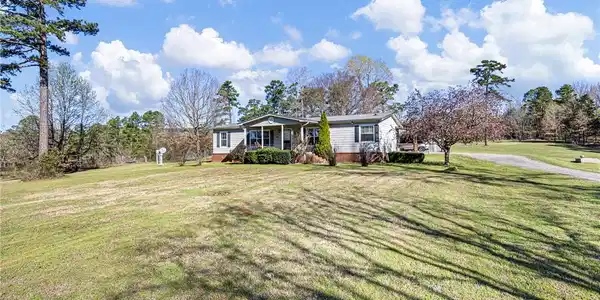 Image 2: Expansive green lawn with a gray-sided residence f