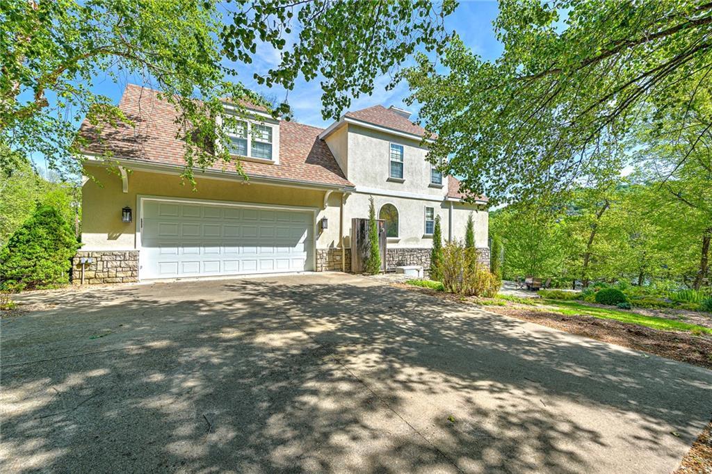 Image 3: View of front facade with stone siding, driveway,