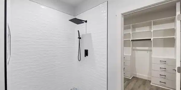 Image 4: Walk-in shower featuring textured white wall tile,