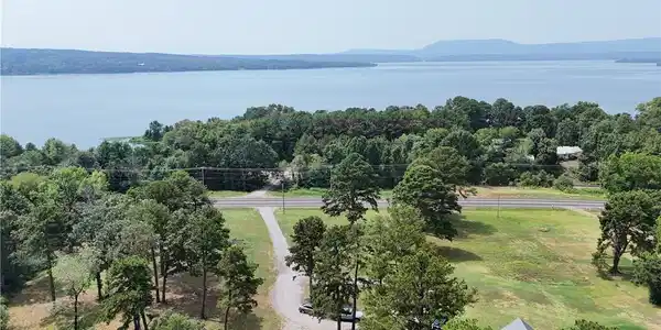 Image 2: Expansive lot featuring a gravel driveway, mature