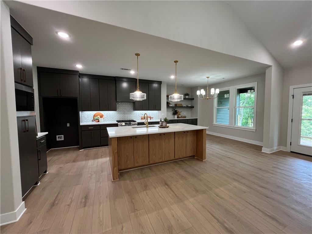 Image 3: Open-concept kitchen and living area featuring woo