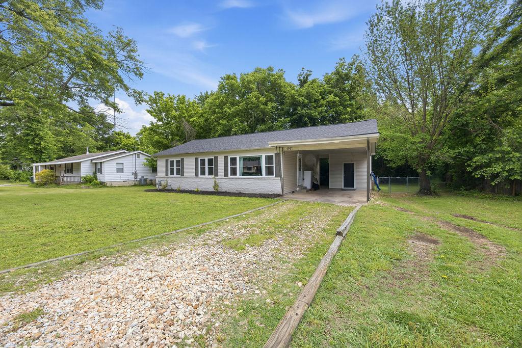 Image 3: Ranch-style exterior with a gravel driveway, cover