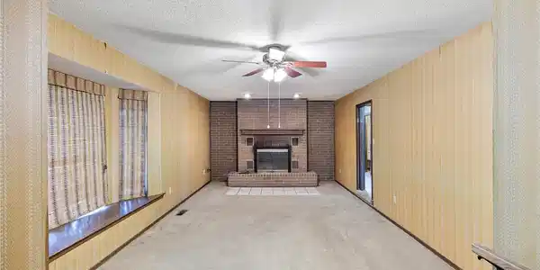 Image 4: Spacious room featuring a brick fireplace with a t