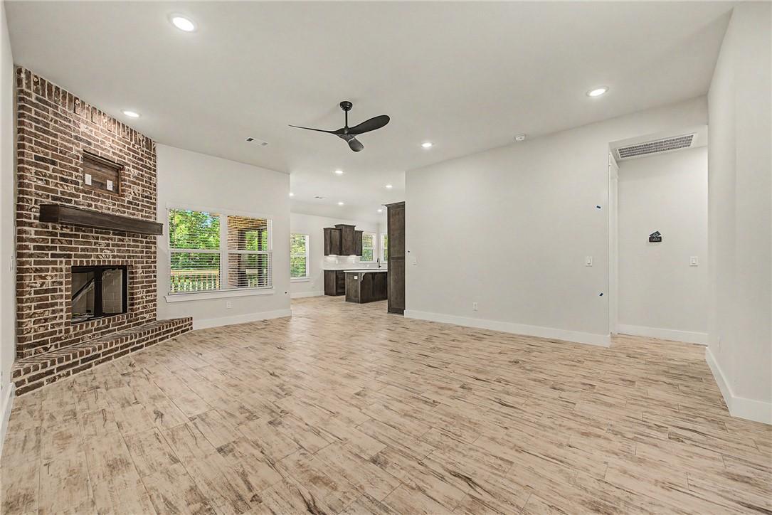 Image 2: Spacious living area featuring a brick fireplace w