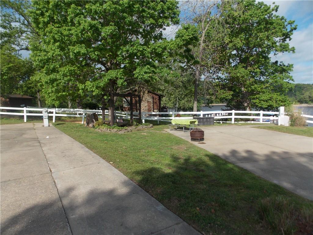 Image 4: Paved lot featuring a white fence, mature trees, a