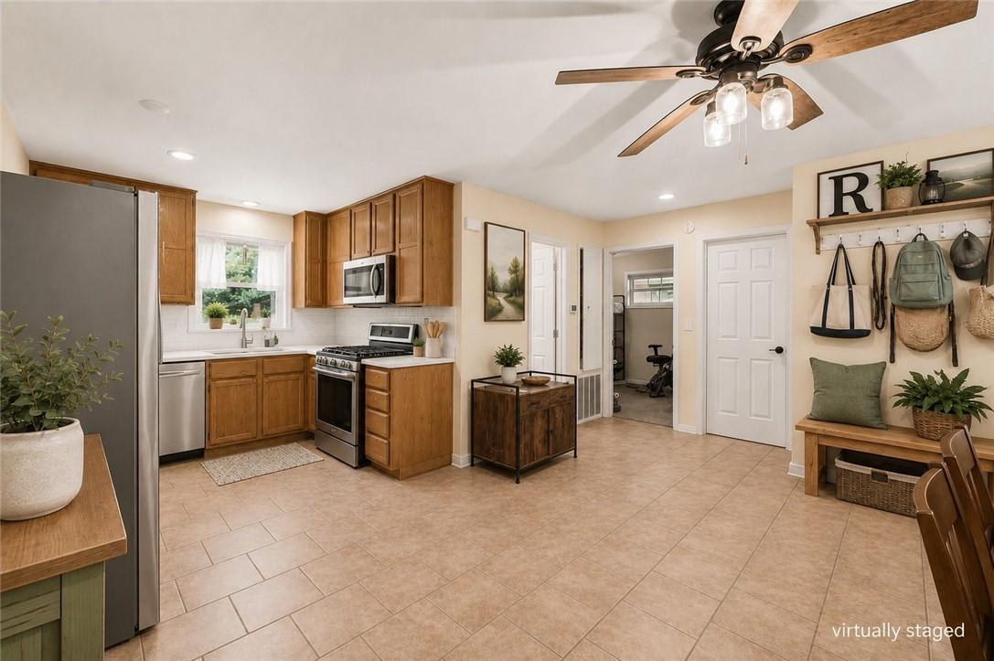 Image 3: Kitchen featuring wood cabinetry, white subway til