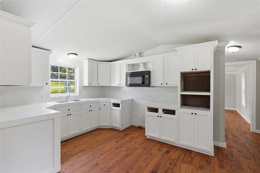 Image 3: Kitchen featuring extensive white cabinetry, wood-