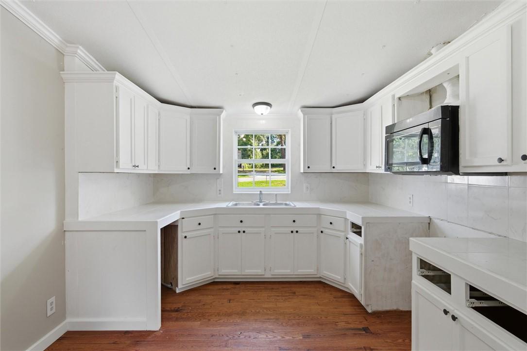 Image 4: Kitchen featuring white cabinetry, light counterto