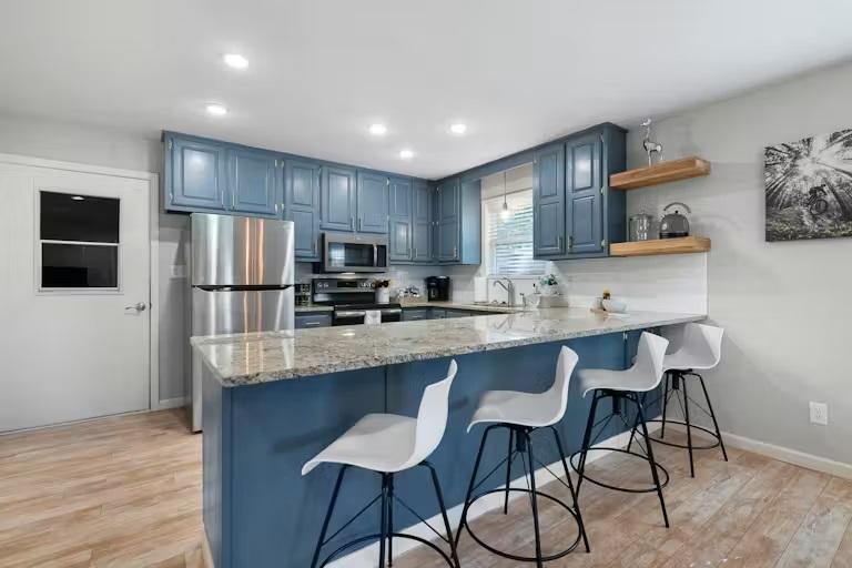 Image 2: Kitchen with a peninsula, blue cabinets, light sto