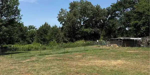 Image 2: Expansive grassy lot with mature trees at the peri