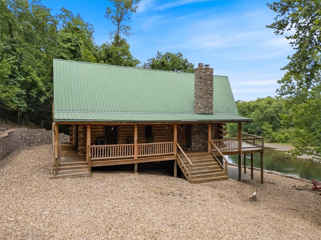 Image 3: Log cabin exterior featuring a green metal roof, s