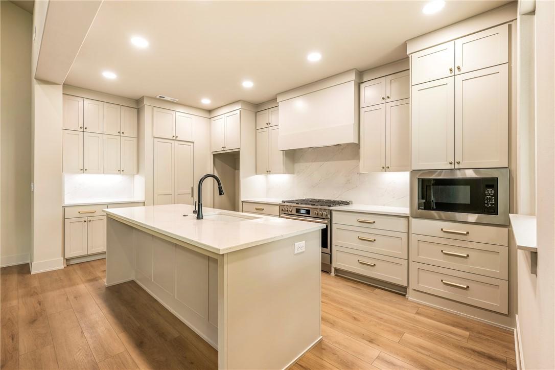 Image 3: Kitchen featuring light-toned cabinetry, a central
