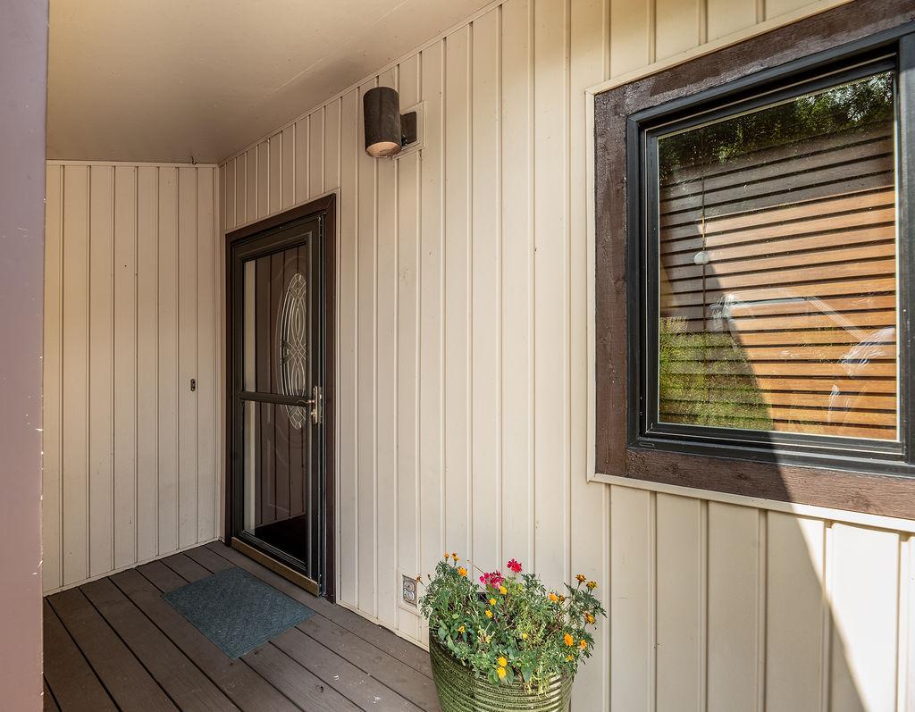 Image 4: Covered entry with vertical siding, a storm door w