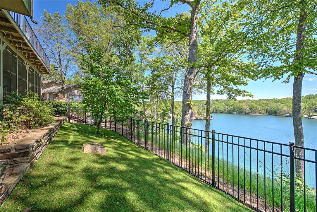 Image 2: Lakeside property featuring a manicured lawn, ston