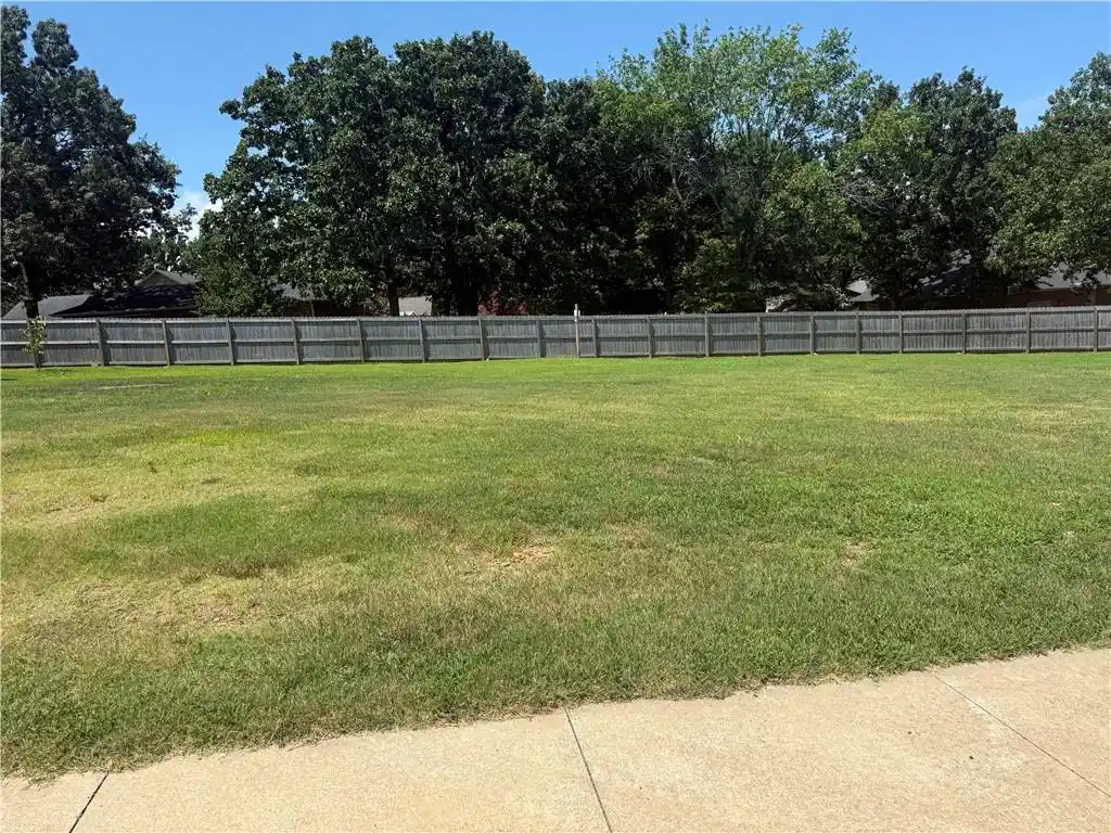 Image 1: Expansive green lawn with a perimeter wood privacy